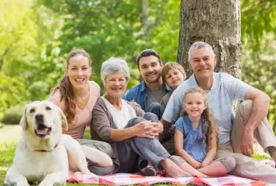 Happy family sitting in the park with a gold lab dog